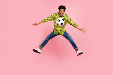 Wall Mural - Full size photo of young cool brunette guy jump with ball wear shirt jeans sneakers isolated on pink background