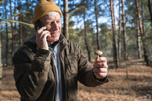Mature Man Holding Mushroom And Having Conversation Via Smartphone