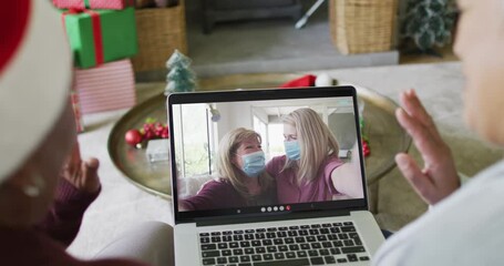 Wall Mural - Diverse senior female friends using laptop for christmas video call with happy family on screen