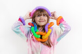 Fototapeta  - Cheerful little girl in unicorn pajamas plays in a popular toy poptube. An exciting children's game with multi-colored plastic pipes.