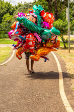 Um Vendedor De Balões Caminhando Em Um Parque.