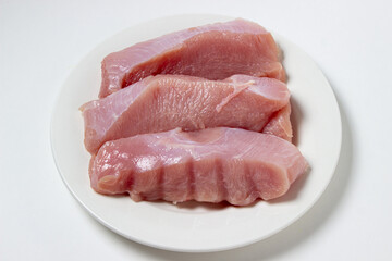 Canvas Print - Raw turkey steaks on a white plate. Turkey breast fillet on a plate. Diet meat