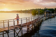 Vacation on tropical island.  Back view of young woman in hat enjoying sunset sea view from wooden bridge terrace, Siargao Philippines.