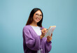Checklist concept. Asian female student in glasses, taking notes in copybook and smiling to camera on blue background