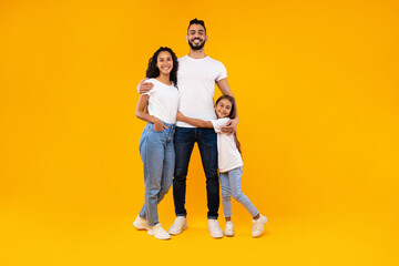 Wall Mural - Middle-Eastern Parents And Daughter Embracing Expressing Positive Emotions, Yellow Background