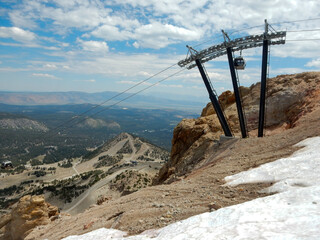  A Valley Overlook from the top of Mammoth Mountains in the California Sierra Nevadas with Melting Snow and Lakes in the Valley also a Ski Lift Tower Cable Support