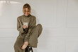 © Look! - Joyful young caucasian lady is using phone while sitting on white background with place for text. Fair-haired beauty in glasses smiles teeth while looking at screen smartphone. Online shopping concept