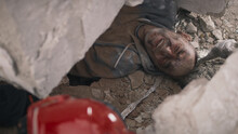 From Above Aged Man Suffering From Pain And Talking With Rescuer While Lying Under Concrete Rubble Of Broken Building