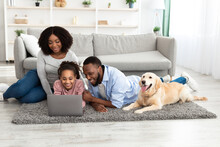 Black Family At Home Using Laptop Relaxing With Dog
