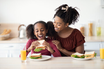 Loving black mother and daughter cuddling while having snack