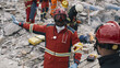 African American man in red uniform pointing away and talking with coworker during rescue mission on remains of broken building after earthquake