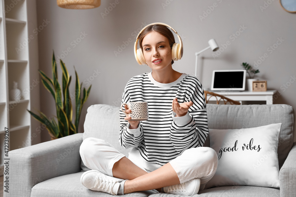 Pretty young woman drinking coffee and video chatting at home