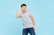 Portrait of happy smiling young Asian man with wireless headphones listening to music on isolated  light blue color background