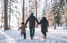 Family Walking In Winter Forest