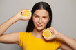 Portrait of attractive woman in yellow t-shirt with lemon fruits. Pretty female model with clear skin and straight brown hair on white background