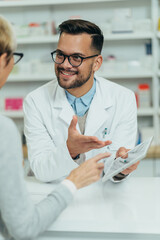 Wall Mural - Male pharmacist selling medications at drugstore to a senior woman customer