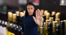 Portrait Of Young Woman Showing Stop Gesture With Hand At Wine Shop