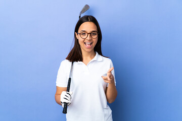 Wall Mural - Young golfer woman over isolated colorful background pointing to the front and smiling