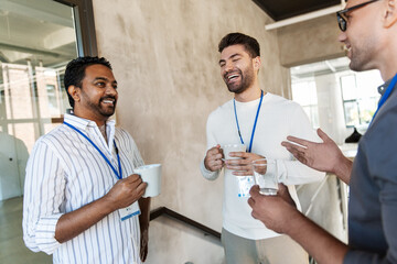 Sticker - business, people and corporate concept - happy smiling businessmen or male colleagues with name tags drinking takeaway coffee at office