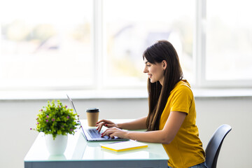 Beautiful young woman working at a office space with a laptop. Concept of smart female business.