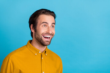 Poster - Photo of cool millennial brunet guy look empty space wear yellow shirt isolated on blue color background