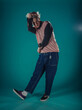 © qunica.com - Young adult man in casual outfit wear looking at camera, holding skateboard near face and standing at studio on blue background
