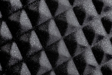 Background made of a macro photo with a smooth diamond-shaped black metal surface with white dots.