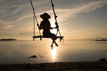 Unrecognizable Woman Sitting On Swing Over Sea At Sunset