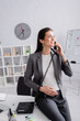 © LIGHTFIELD STUDIOS - happy pregnant businesswoman talking on retro telephone in office.