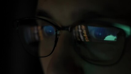 Businessman working at night looking at monitor, reflections in eyeglasses. Traiding