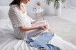 © LIGHTFIELD STUDIOS - cropped view of happy pregnant woman holding baby clothes in bedroom.