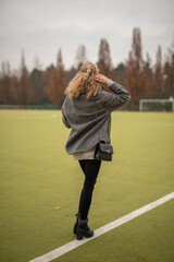 Wall Mural - Wunderbare Schöne Frau mit Blondem Haar  und Grauen Mantel in der Winter Zeit in Berlin Grüner Sport Platz