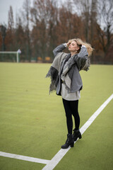 Wall Mural - Wunderbare Schöne Frau mit Blondem Haar  und Grauen Mantel in der Winter Zeit in Berlin Grüner Sport Platz