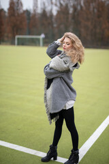 Wall Mural - Wunderbare Schöne Frau mit Blondem Haar  und Grauen Mantel in der Winter Zeit in Berlin Grüner Sport Platz