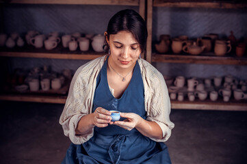 Wall Mural - Young woman master shows the finished clay product in art studio. The concept of craft creativity.