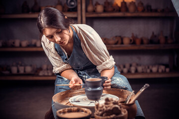 Wall Mural - Young female potter working on a potter's wheel.