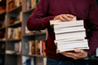 © Drazen - Unrecognizable man holds stack of books while studying in library.