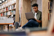 © Drazen - Young black student uses laptop while  e-learning at college library.