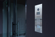 Entrance Doorbell In A Multi-apartment Building, With A Video Surveillance Camera, On A Dark Wall