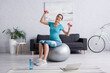 © LIGHTFIELD STUDIOS - happy pregnant woman exercising on fitness ball with dumbbells near laptop.