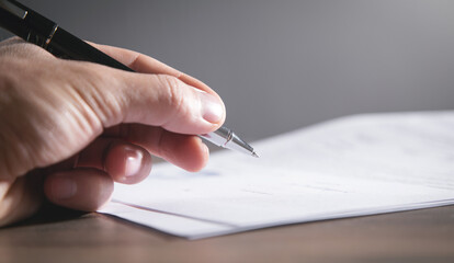 Human hand signing contract in office.