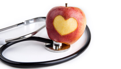 Carving heart on an apple with a stethoscope. Healthy lifestyle concept