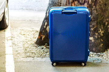 suitcase on castors costs on the street. case, trunk, bag, valise, portmanteau. Concept moving, travel, trip, flight. Concept Summer rest, holidays.