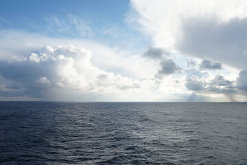 View from vessel on heavy rainfall clouds bringing abundant rainfall and atmospheric precipitation partly interrupted by bleu sky observed on Pacific ocean in winter season during calm weather.