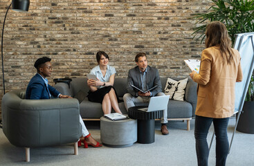 Wall Mural - Corporate Business: Mixed-Race Team Working Together in the Open Plan Office. 
Group of five multi-ethnic business people sitting at desk and analyzing business report on a laptop computers and papers