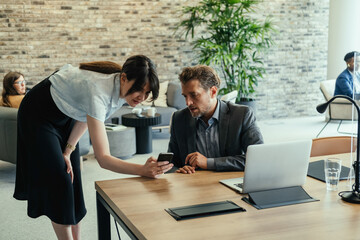 Wall Mural - Corporate Business: Two Colleagues Looking in Mobile Phone Together in the Modern Open Plan Office