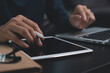 © tippapatt - Man working on digital tablet and laptop computer at home office, close up
