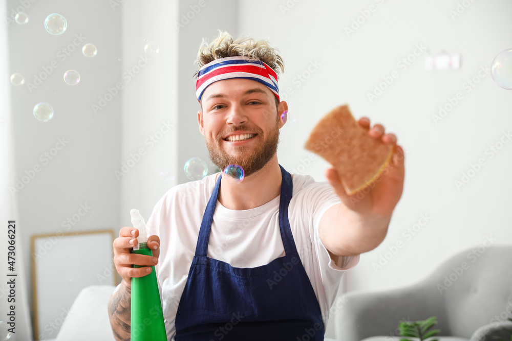 Handsome young man with cleaning sponge and detergent at home