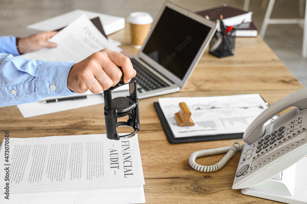 Male notary public attaching seal to documents in office