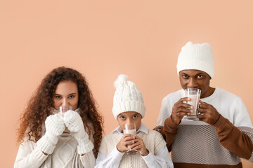 Poster - African-American family in winter clothes and with tasty hot chocolate on color background